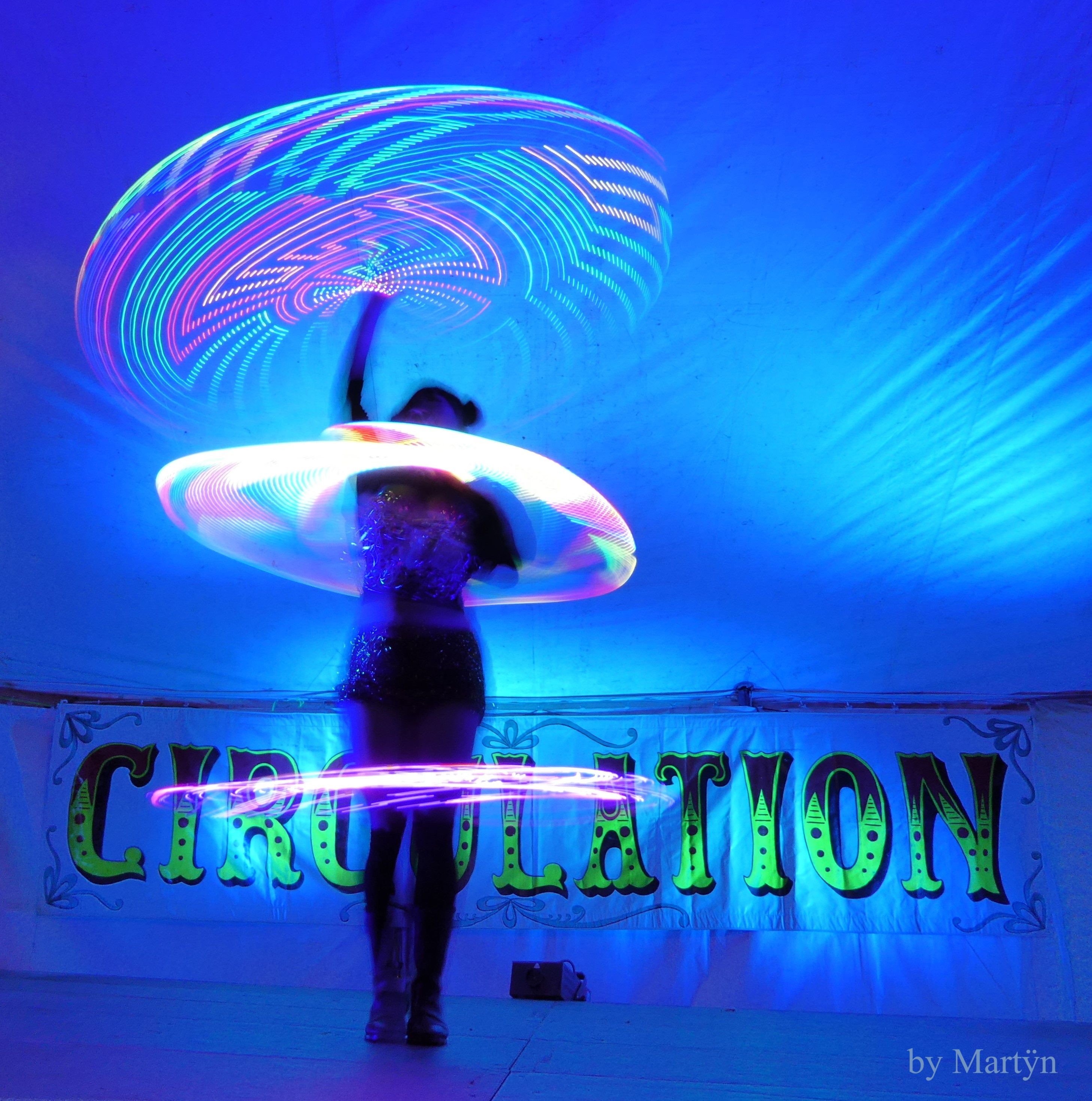 Someone with LED hulahoops in a swirl of light around them